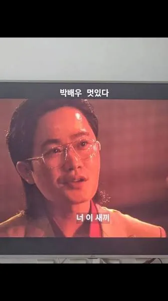 A photograph of a television screen showing Park Seong-il in character, with Korean captions on screen.